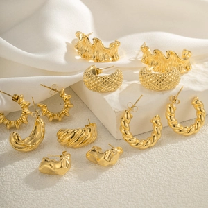 Collection of various minimalist 18k gold plated C-shape hoop earrings on white silk