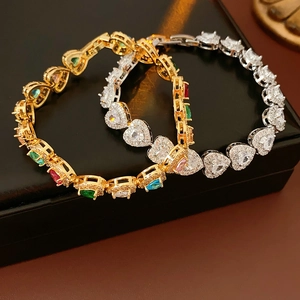 Macro view of heart-cut zircon bracelets in gold and silver on a black jewelry box