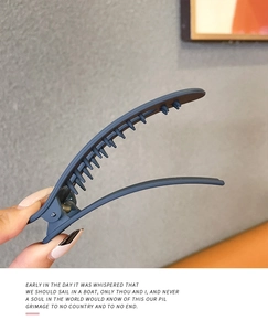 Detail showing the non-slip teeth and metal spring of a matte fog blue hair clip
