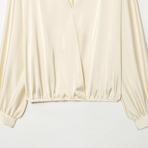Élégante blouse en satin crème avec col en V, manches longues et détails de plis à l'ourlet