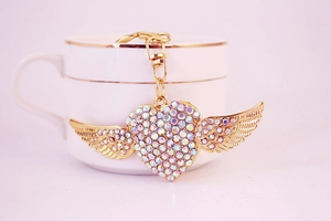 Detailed shot of a golden heart-shaped wing keychain with shimmering rhinestones and clasp