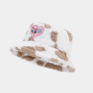 Close-up of plush bucket hat featuring cow print and a pink heart cat patch