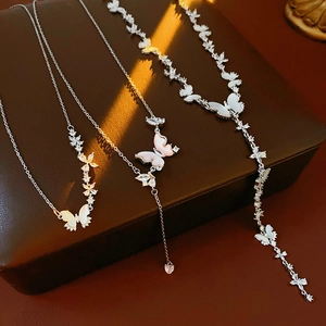 Détail de colliers papillon en argent avec zircon et nacre sur un coffret à bijoux
