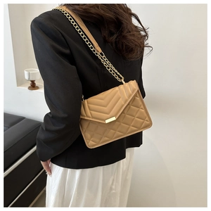 Detail of light brown quilted chain bag with gold hardware and V-pattern on PU leather