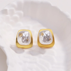 Détail macro de boucles d'oreilles carrées plaquées or 18k avec perles et feuilles d'or