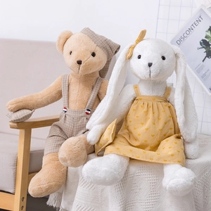 Plush teddy bear and bunny set in cute outfits sitting on a wooden chair with lace decor