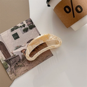 Detail of oversized cream marble acetate hair claw clip with Creation France logo