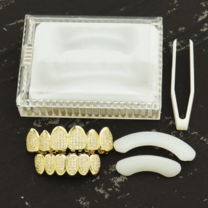 Iced out hip hop gold grillz set with clear zircons, including storage box and tweezers