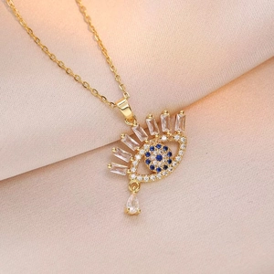Golden Evil Eye pendant necklace with blue zircon and teardrop crystal on satin background