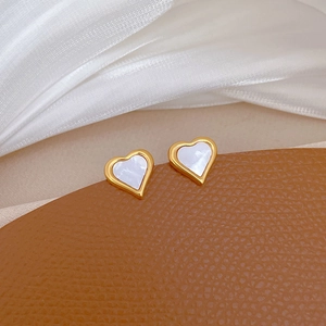 Macro shot of minimalist gold heart earrings with white mother-of-pearl inlay