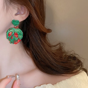 Close-up of Halloween glitter heart and skull apple earrings worn on a female model