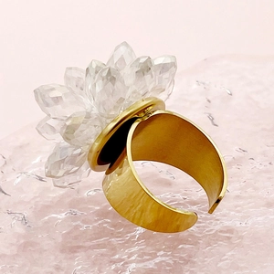 Detail of a golden open ring featuring a clear crystal lotus flower on pink stones