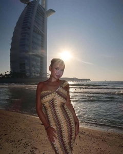 Detail of the one-shoulder lace dress featuring yellow and purple wave patterns on the beach