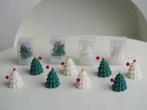 Detail view of mini hand-painted Christmas tree candles in green and white with PET boxes