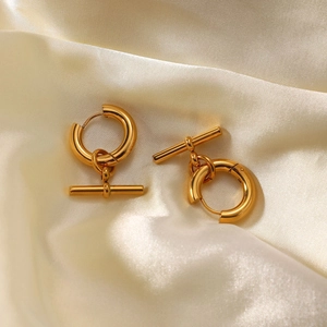 Golden stainless steel hoop earrings with removable T-bar pendant on silk background