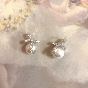 Detail shot of silver bow earrings with zircon stones and hanging white pearls
