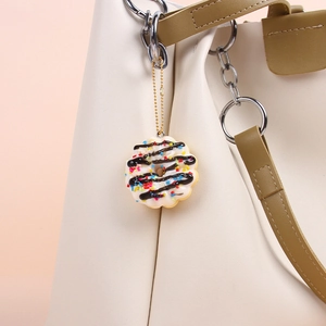 Realistic donut keychain with white icing and sprinkles on a cream leather handbag