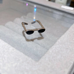 Close-up of silver-tone sunglasses-shaped open ring with black enamel details