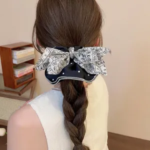 Chouchou avec nœud à pois et motif paisley porté sur une queue de cheval basse par un modèle