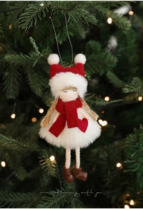 Detail of plush Christmas girl ornament with red heart hanging on decorated tree