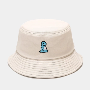 Detailed close-up of blue dinosaur embroidery on a beige cotton bucket hat