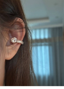 Close-up of sparkling zircon ear cuff and silver stud earring set for women