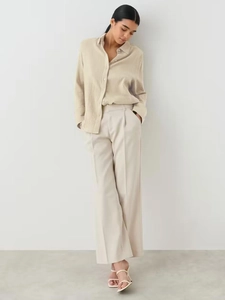 Detail of light beige textured cotton shirt and cream wide-leg trousers for women