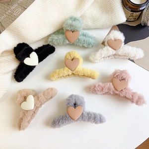 Flat lay of multiple colorful plush hair claws with heart accents on cozy background