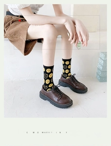 Close-up of black crew socks with yellow smiley patterns worn with brown leather shoes