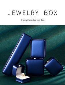 Detail of luxury navy blue jewelry boxes featuring gold crown clasps and cream velvet lining