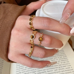 Detail of four gold plated rings with tiger eye stone and micro-inlaid zircon accents