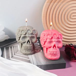 Detail of skull candles with floral wreaths and lit wicks on a wooden tray