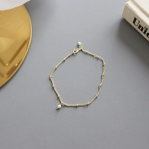 Elegant gold beaded chain bracelet featuring a single pearl pendant and a secure lobster clasp