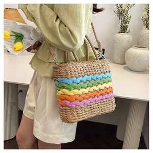 Rainbow striped straw woven bag held by model wearing a light green top and white shorts