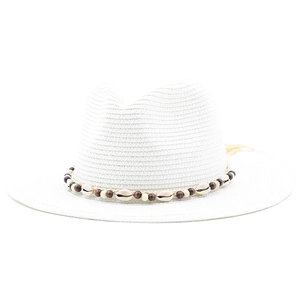 Detail of white straw fedora hat featuring a decorative shell and wooden bead band