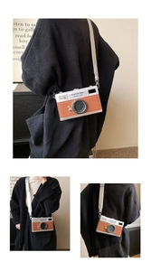 Detail of silver and brown camera-shaped crossbody bag with wide shoulder strap