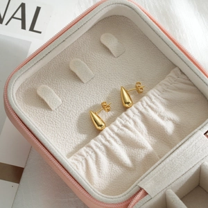 Golden stainless steel teardrop earrings on a pink leather jewelry box showcase