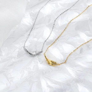 Macro shot of gold and silver leaf pendants with fine zircon stones on white paper