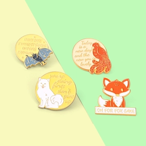 Vue à plat de broches en émail colorées avec citations et motifs d'animaux