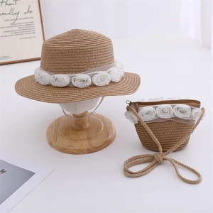 Detail of cream rose lace decorations on a natural straw hat and matching crossbody bag set