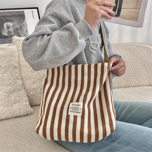 Dettaglio di una borsa tote in tela a righe con trama marrone e beige e tracolla reg