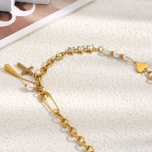 Close-up of gold cross pendant with pearls and star charms on a chunky metal chain