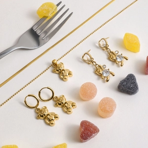 Macro shot of gold bear jewelry set with zircon necklace and earrings on white background