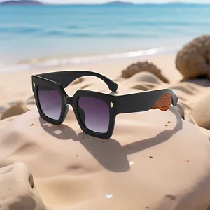 Square fashion sunglasses with purple gradient lenses and cork texture arms on beach sand