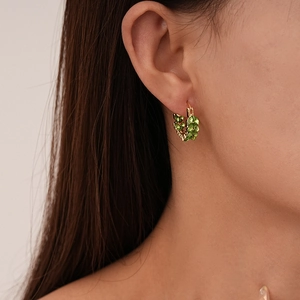 Macro shot of gold ear cuff featuring olive green marquise-cut gems in a leaf pattern