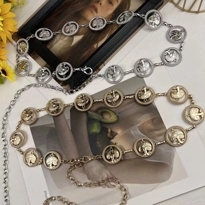 Detail of silver and gold metal waist chains with mushroom patterns on a fashion magazine