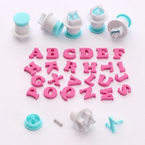 Macro detail of alphabet cookie cutters showing internal spring mechanism and pink letters