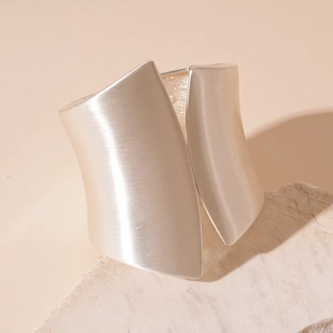Detail of silver matte brushed finish on wide geometric irregular open metal bangle