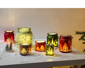 Détail de divers photophores de Noël en verre avec motifs de renne et flocons de neige