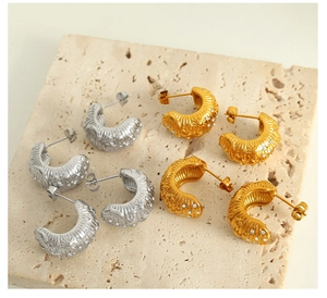 Detailed view of C-shaped 18k gold and silver earrings with zircon and spiral texture